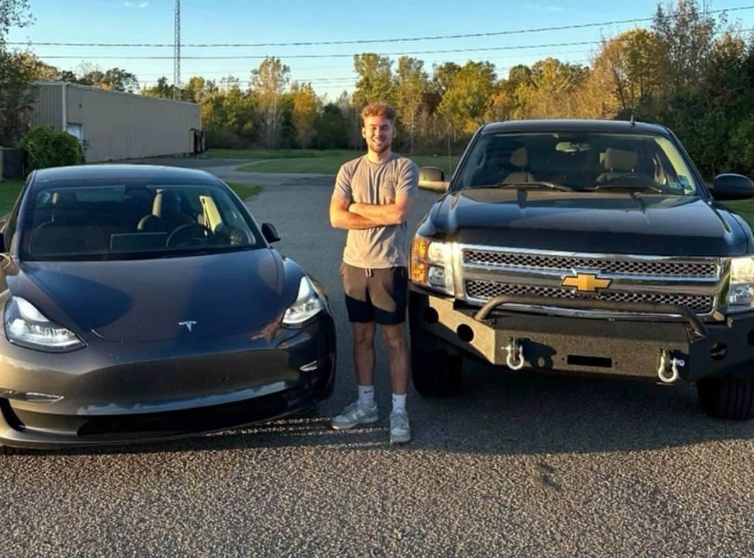 Nick standing between his Tesla Model 3 and his black Chevy truck