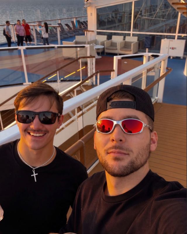 Nick and a friend taking a selfie on a cruise ship deck at sunset in Ensenada, Mexico